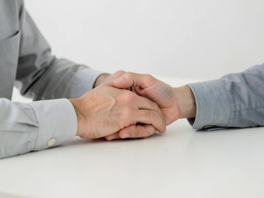 Close-up of hands shaking over a clean desk, business casual attire