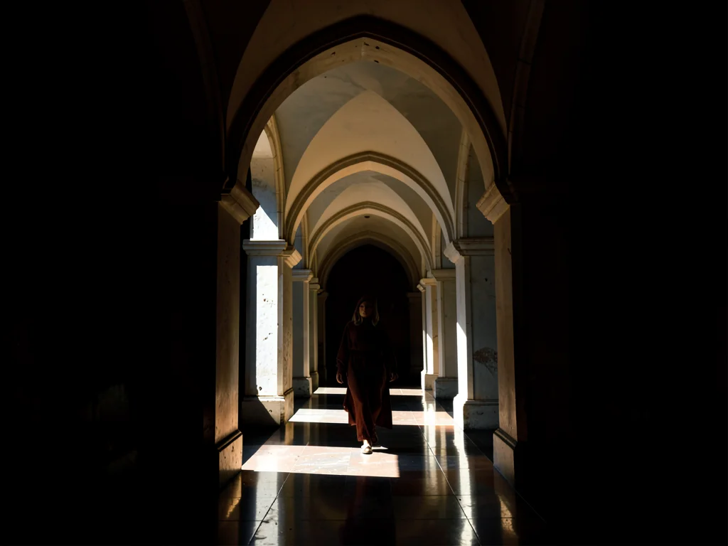 Long arcaded corridor where every other arch holds darkness and every alternate 