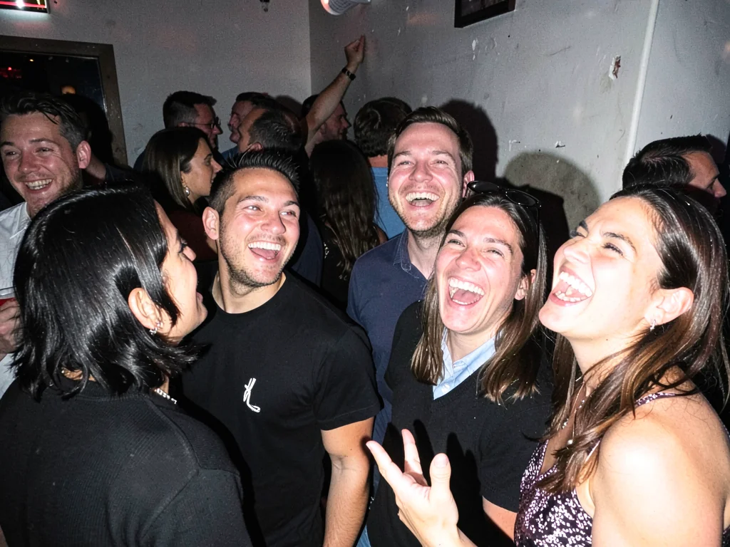 Party guests mid-laugh at crowded bar