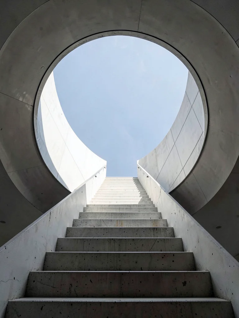 Concrete staircase viewed straight up, steps receding into circle of sky