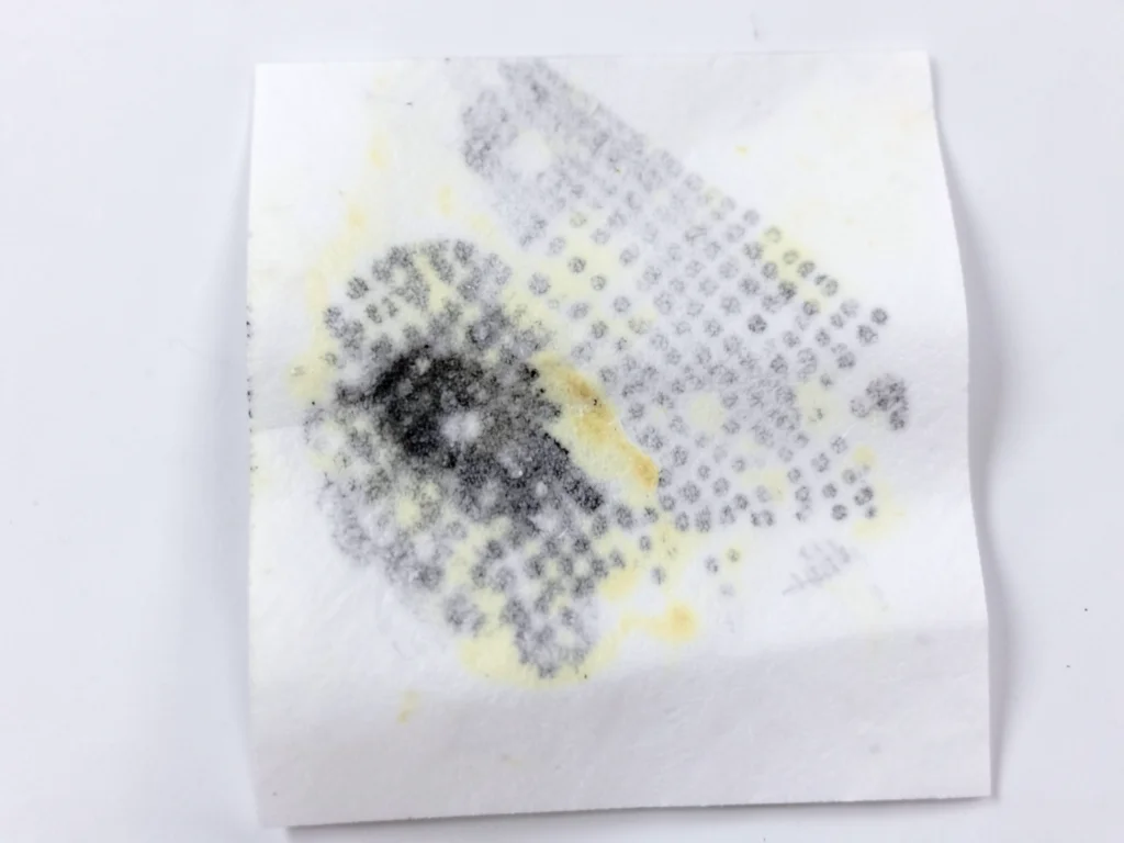 Thermal paper heat damage, dark smear where warm object touched the surface, uni