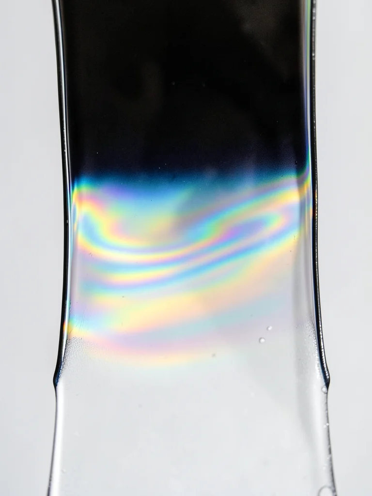 Soap film draining on vertical frame, thick bottom band (silver-white) thinning 