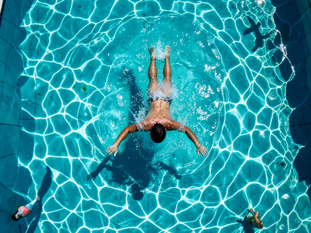 A swimmer emerging from underwater, the moment of breaking the surface, water sh