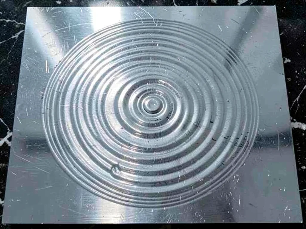 Water surface on metal plate showing circular standing wave pattern from 432Hz t