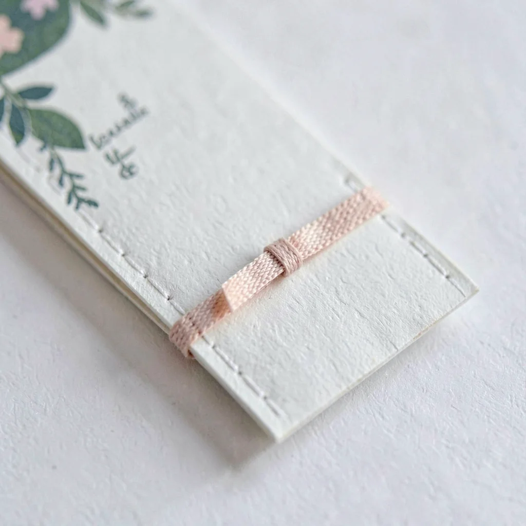 Macro of a small chapbook insert with sewn-in ribbon bookmark