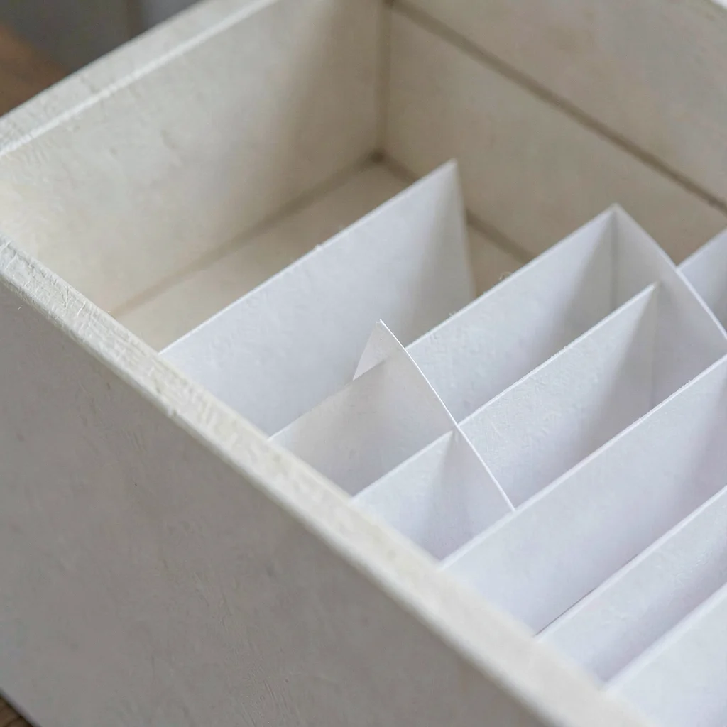 Macro of folded paper dividers fitted into a drawer compartment, soft fiber grai
