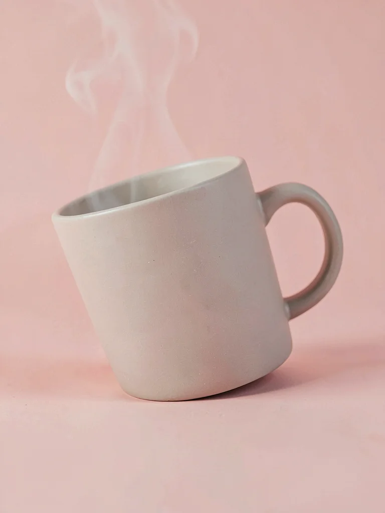 Curvy ceramic mug with matte glaze captured at slight tilt on a blush pink seaml