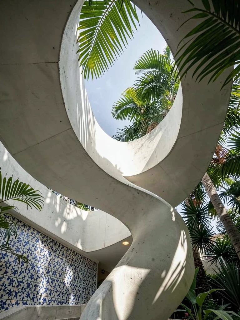 Spiral exterior staircase in white concrete, viewed from below, palm fronds inte