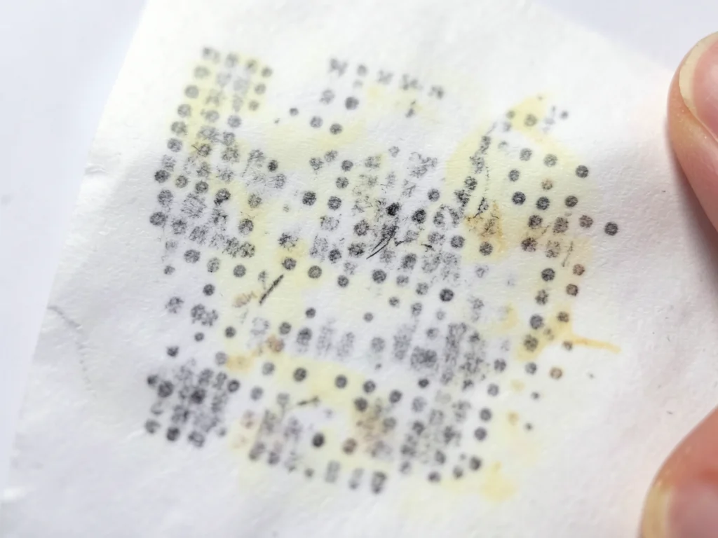 Thermal paper reacting to friction, fingernail scratch leaving dark line on whit