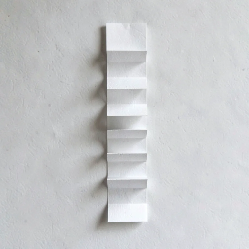 Vertical accordion of folded press-clip rectangles climbing the frame, raking sh