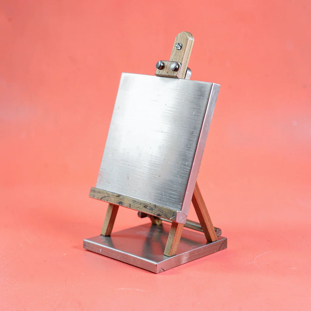 single brushed-steel artist-easel mini desktop unit at slight tilt on a saturate