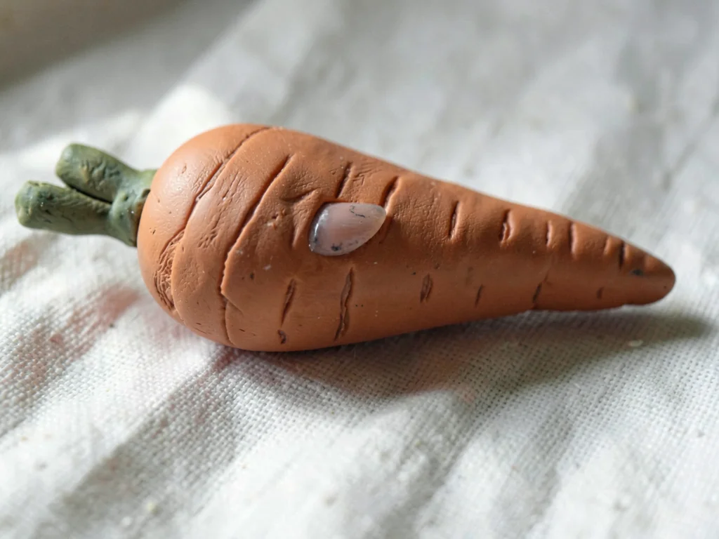 Gleaned terracotta carrot with a slumped tip and fingernail-grooved skin, on pla