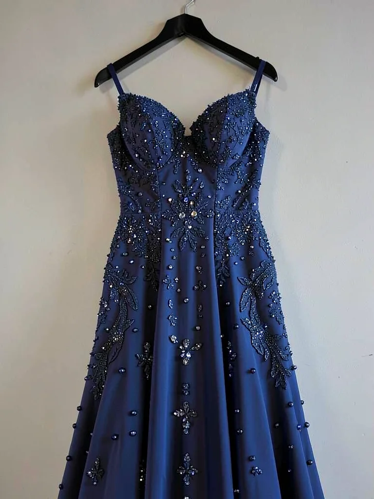 Wedding dress preserved in deep blue, every bead and stitch visible, hanging alo