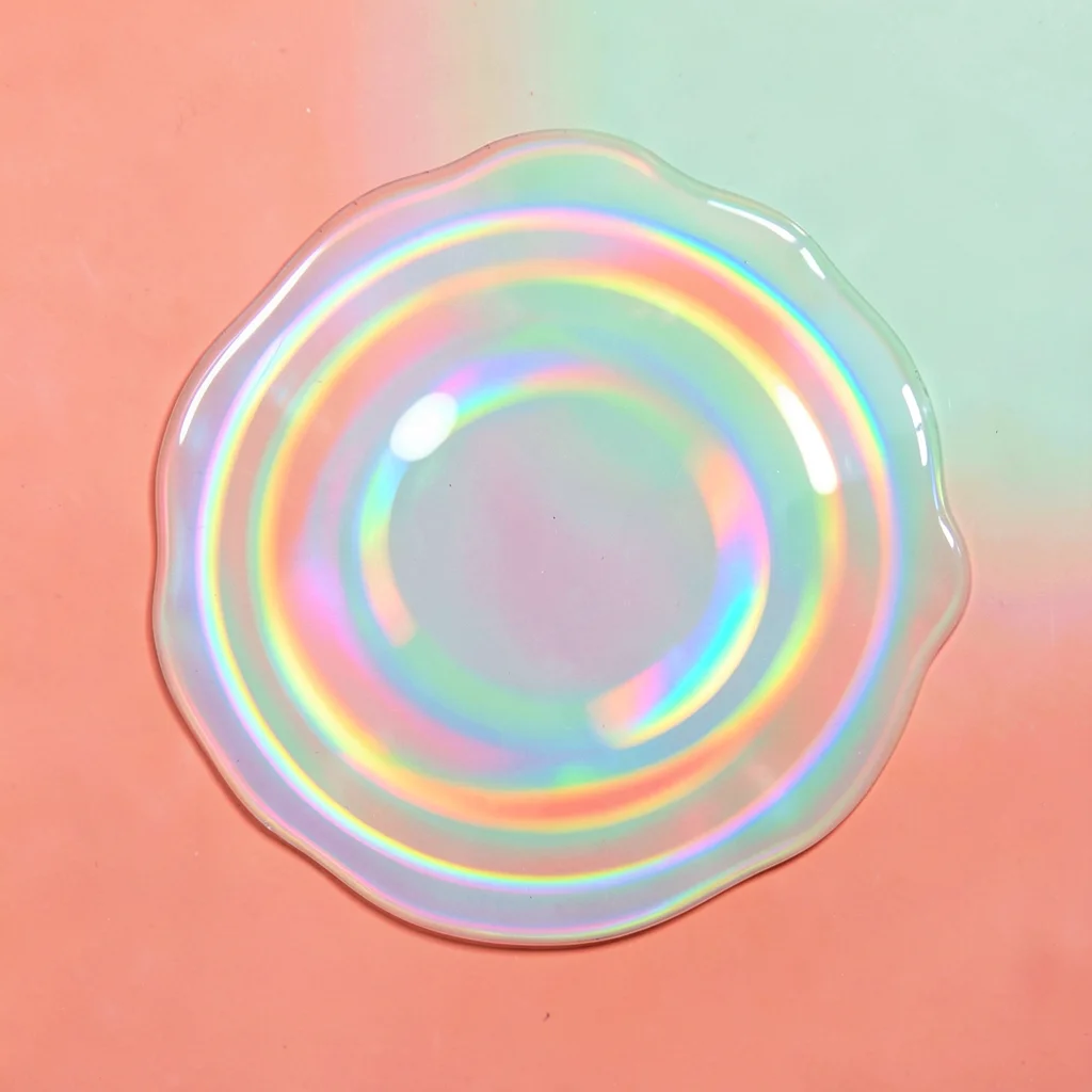 Iridescent oil-slick puddle viewed top-down with concentric rainbow rings on a c