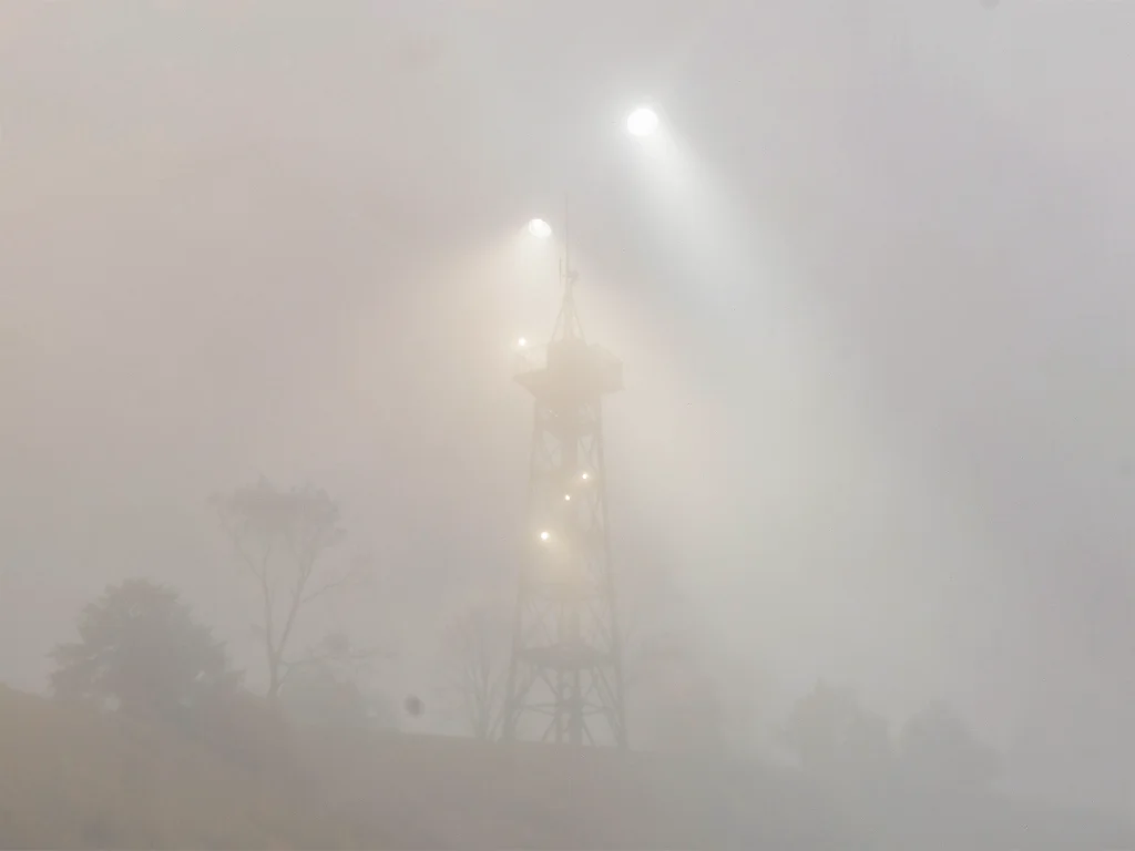 Twin range lights blinking in dense fog, only the closer tower drawn in detail, 