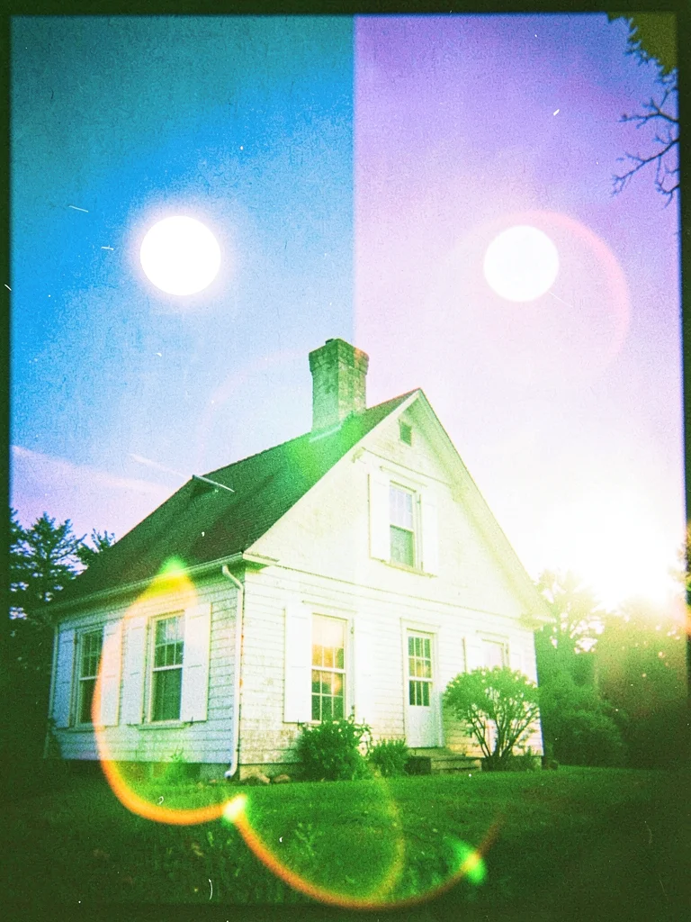 White painted shutters of an old farmhouse glowing under a sky split between blu