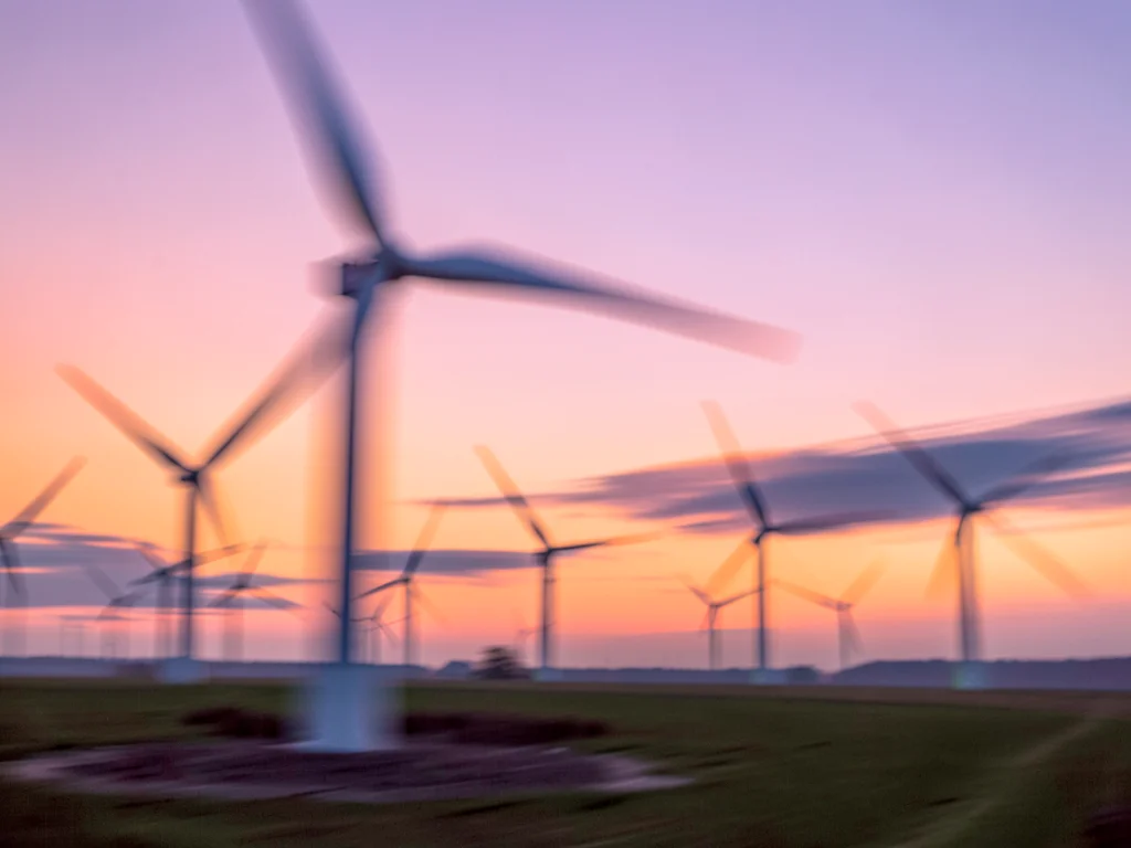 Wind turbines at dawn blurring against pink and orange gradient sky