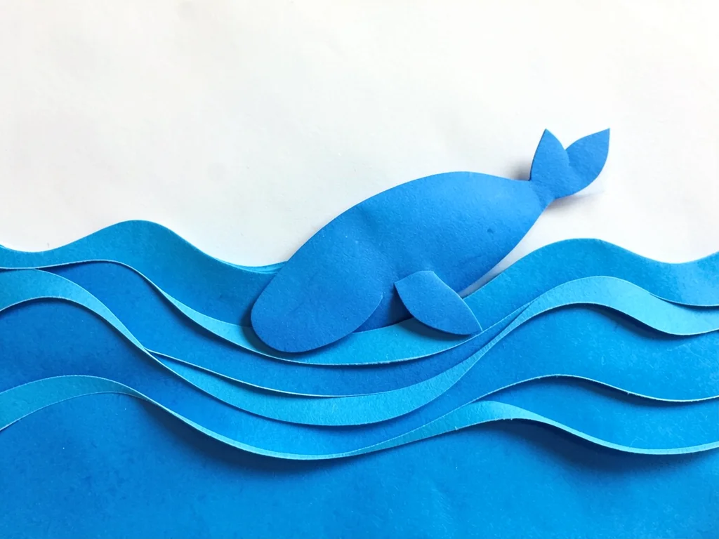 Paper craft ocean waves in layers, whale made of blue paper breaching surface