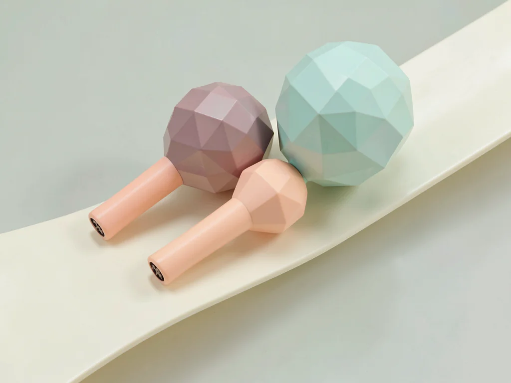 Shaken mint lowpoly maracas with peach handles and faceted dusty-pink bulbs, on 