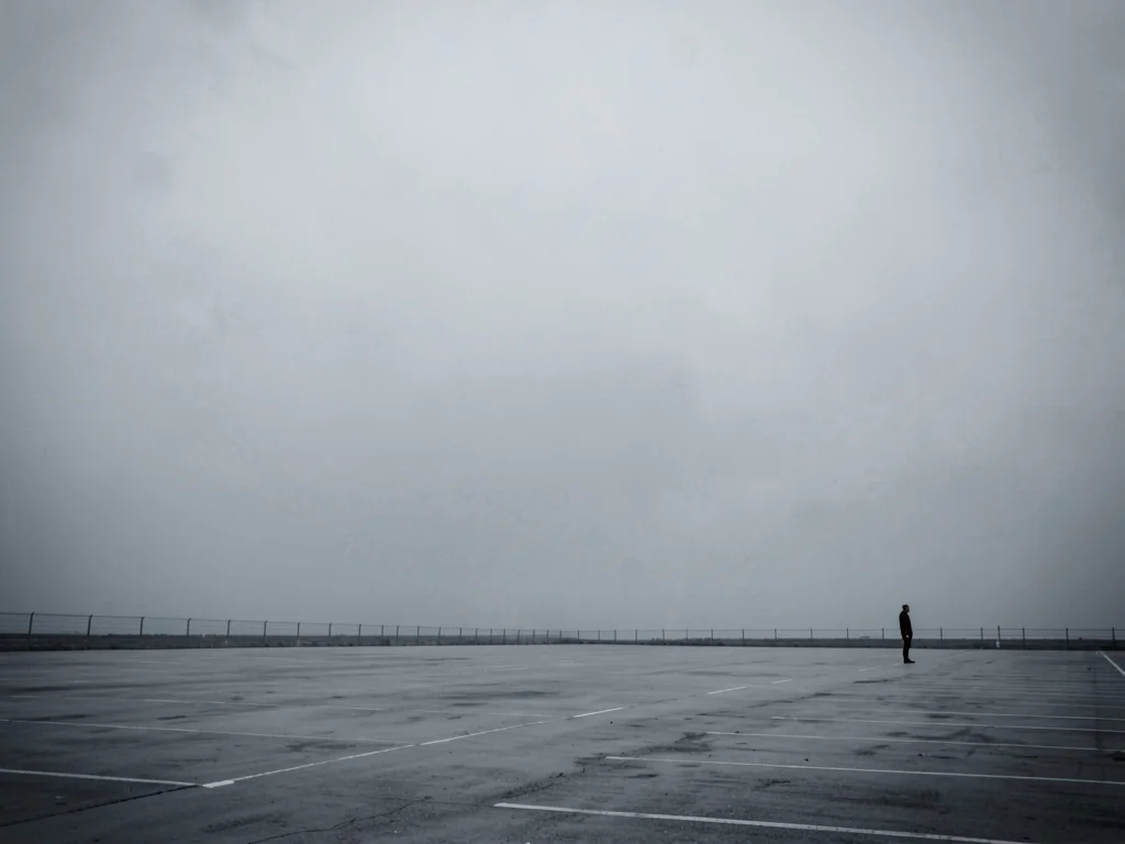 Lone figure at extreme corner of massive empty parking lot