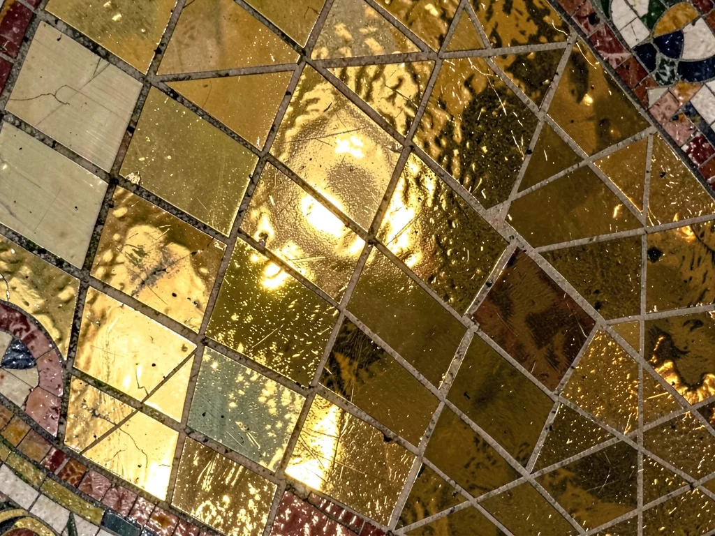 A gold glass tesserae section from a ceiling mosaic, tiles at slight angles refl