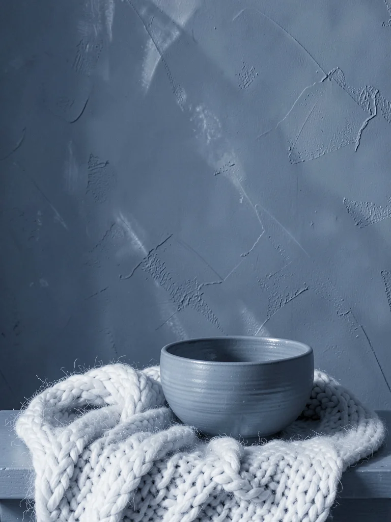 Slate blue study, ceramic bowl, wool blanket, painted wall, cool tonal control