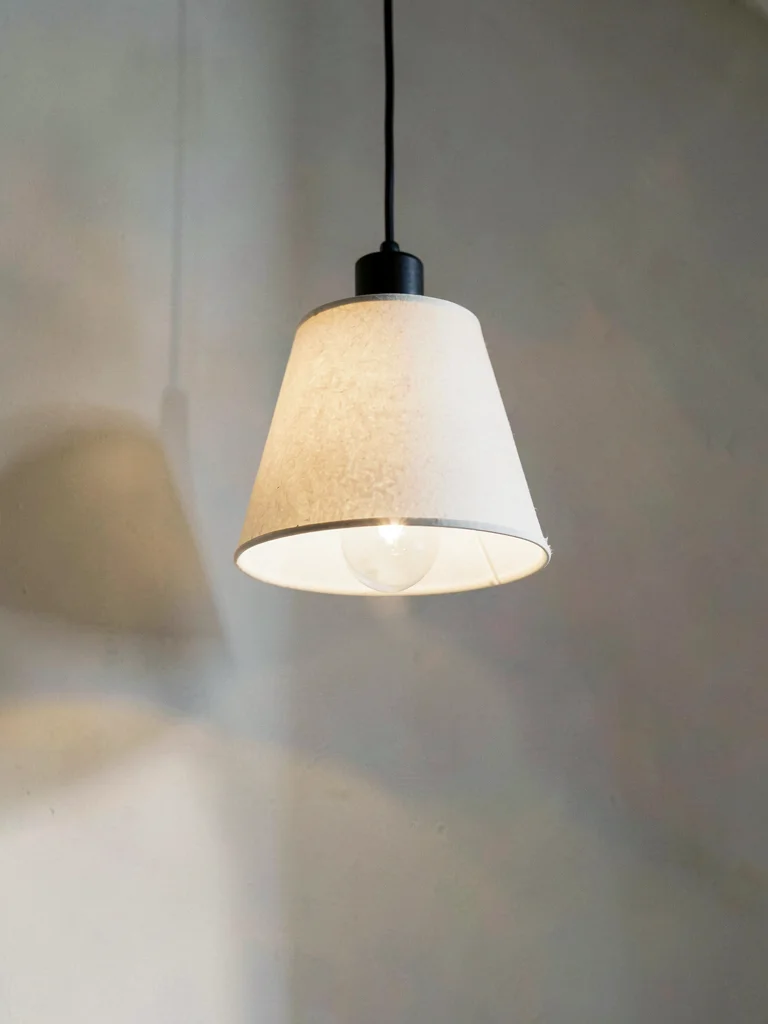 A small lamp photographed from below, paper shade glowing only with soft borrowe