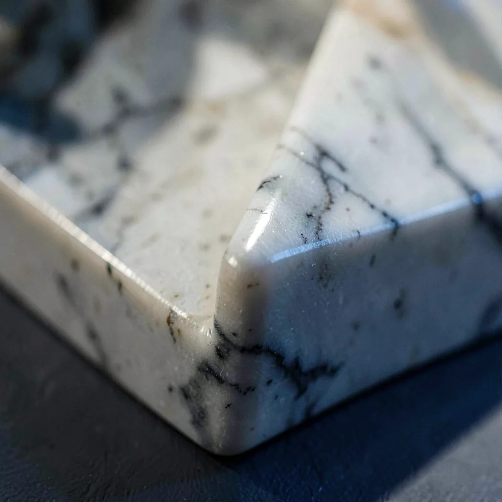 Mineral-cut close-up of a polished marble sculpture detail with a single sharp e